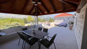 une terrasse couverte avec une table et des chaises. dans l'établissement Villa Dalma, à Čilipi
