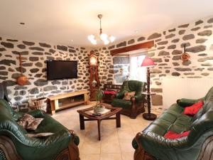 a living room with leather furniture and a stone wall at Gîte Paulhac, 5 pièces, 11 personnes - FR-1-742-80 in Paulhac
