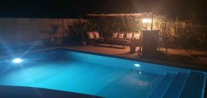 a swimming pool at night with a table and a bench at Le Petit Bergeron in Mazion