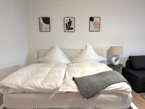 a white bed with four pillows on top of it at Neue, attraktive Wohlfühlwohnung mit traumhafter Aussicht in Neubulach