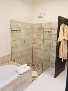 a bathroom with a tub and a glass shower at The Retreat Swellendam in Swellendam