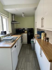 a kitchen with white cabinets and a black refrigerator at Idyllic Retreat in Dalton-In-Furness Sleeps 3! in Dalton in Furness