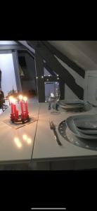 a table with red candles and plates and a glass at Studio cosy atypique in La Ferté-Bernard