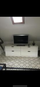 a flat screen tv sitting on top of a white cabinet at Studio cosy atypique in La Ferté-Bernard