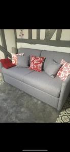 a gray couch with red and white pillows on it at Studio cosy atypique in La Ferté-Bernard