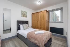um quarto com uma cama, um armário e uma televisão em Charles Alexander Short Stay - The Banks Apartments em Blackpool