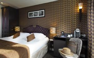 パリにあるホテル デュ プランス ウジェーヌのベッドとデスクが備わるホテルルームです。