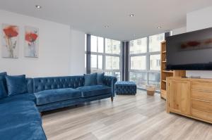 sala de estar con sofá azul y TV de pantalla plana en Charles Alexander Short Stay - The Banks Apartments en Blackpool