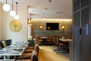 a restaurant with tables and chairs and a tv on the wall at Apparthotel 37 Lodge - Courbevoie La Défense in Courbevoie