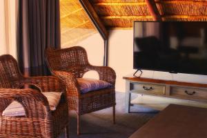 sala de estar con sillas de mimbre y TV de pantalla plana en Clivia Lodge, en Vanderbijlpark