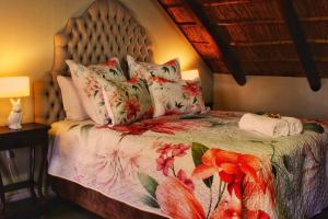 a bedroom with a bed with a floral bedspread at Clivia Lodge in Vanderbijlpark