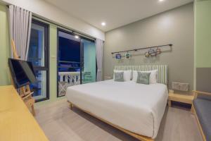 Chamemon Bed Phuket Town في فوكيت تاون: غرفة نوم بسرير ابيض كبير وتلفزيون