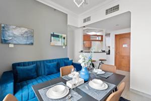 StoneTree - Stylish 1BR near Marina Walk في دبي: غرفة معيشة مع أريكة زرقاء وطاولة
