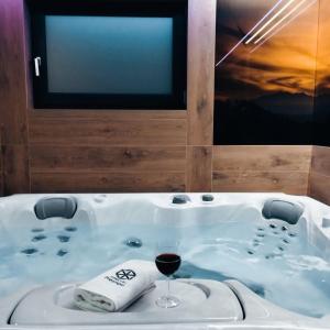 a bath tub with a glass of wine and a tv at Jaworki Prestige SPA in Jaworki