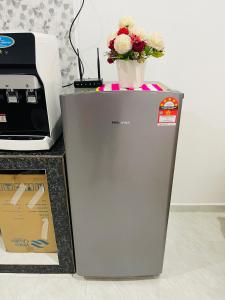 a silver refrigerator with a vase of flowers on top at Homestay CikguMa - Netflix & Wifi in Kota Bharu