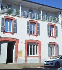a white building with windows and a car parked in front at Tarbes Immeuble résidentiel labelisé et classé Proche des Halles Marcadieu et Brauhauban et du Parc des expositions - Appartements Appaloosa T2 Rdc et Pyrénéa T2 au 1er étage avec terrasse couverte -Parking gratuit- in Tarbes
