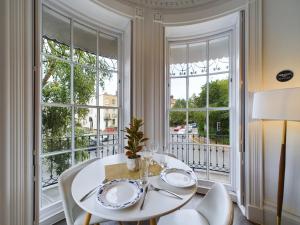 a dining room with a white table and chairs and windows at Belle Vue Regency King size w Free Parking in Cheltenham