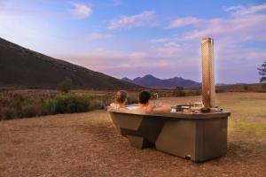 zwei Personen sitzen in einer Badewanne auf einem Feld in der Unterkunft Drie Kuilen Nature Reserve in Touwsrivier