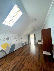 an attic room with a skylight and a room with wooden floors at Borovik in Novosilki