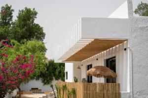 een wit huis met een rieten parasol en bomen bij Perfect villa for your vacation in Dubai