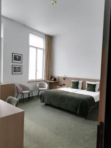 a bedroom with a large bed and a window at Hotel Messeyne in Kortrijk