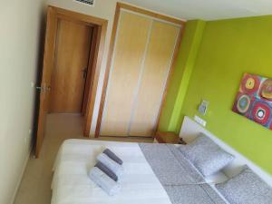 um quarto com uma cama branca e paredes verdes em Sunny place. em Guardamar del Segura