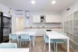 een witte keuken met witte tafels en blauwe stoelen bij LaResiBCN minimum 30 nights in Barcelona