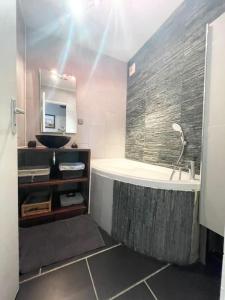 uma casa de banho com uma banheira, um lavatório e um espelho. em Grand appartement idéalement situé em Villeurbanne