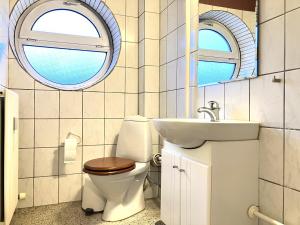 a bathroom with a toilet and a sink and two windows at One-Bedroom Apartment Located In The Charming City Of Odense, in Odense +25 photos
