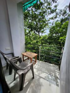 - un balcon avec deux chaises, une table et un arbre dans l'établissement The Coastline Stays, à Arambol