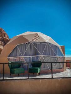 a tent with two green chairs in front of it at rum rema camp in Wadi Rum