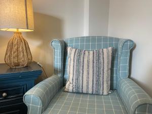 a blue chair with a pillow next to a lamp at The Courtyard Rooms in Brightlingsea