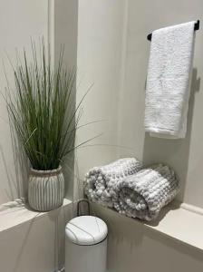 a bathroom with a toilet and a plant and towels at The Courtyard Rooms in Brightlingsea