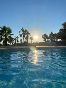 einen Pool mit Palmen und Sonnenuntergang in der Unterkunft Apartment Sol Dorado - Mar Menor Golf Resort in Torre-Pacheco