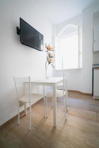 uma mesa de jantar branca com uma televisão na parede em APT per coppie nel cuore di Desenzano CASTELLO em Desenzano del Garda