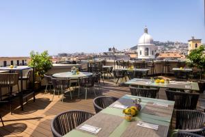 a patio with tables and chairs on a roof at UNAHOTELS Napoli in Naples