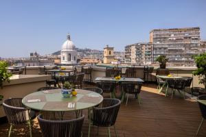 a balcony with tables and chairs and a view of a city at UNA Hotels Napoli in Naples