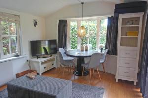ein Wohnzimmer mit einem Tisch mit Stühlen und einem TV in der Unterkunft Vechtdalchalet de Berk, 5 sterrenpark Capfun Stoetenslagh in Rheezerveen