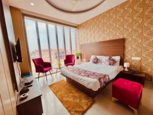 a bedroom with a large bed and red chairs at Hotel The Pearl, Zirakpur - A Luxury Family Hotel in Chandīgarh