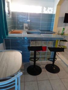 a kitchen with two bar stools in front of a counter at Studio proche aéroport 2perswifi in Matoury