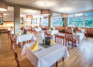 a restaurant with white tables and chairs and windows at JUFA Hotel Bad Aussee in Bad Aussee