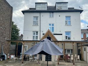 a white building with an umbrella in front of it at Aron Guest House in Ealing