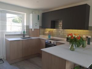 a kitchen with brown cabinets and a vase of flowers on a counter at Luxury Holiday Home in St. Leonards