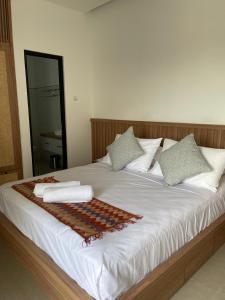 ein großes Bett mit weißer Bettwäsche und Kissen darauf in der Unterkunft Aroom Homestay in Kerobokan