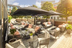 un patio al aire libre con sofás, mesas y una sombrilla en Crowne Plaza Leeds, an IHG Hotel, en Leeds