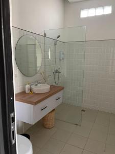 ein Bad mit einem Waschbecken und einer Dusche mit einem Spiegel in der Unterkunft Aroom Homestay in Kerobokan