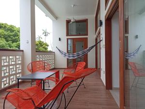 un patio con sillas rojas, una mesa y una hamaca en Morona Flats & Pool - 150 m2, en Iquitos