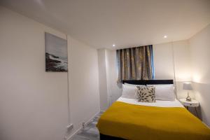 Remarkable 3-Bed Apartment in London في لندن: غرفة نوم بسرير وبطانية صفراء