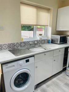 a kitchen with a washing machine and a microwave at Serenity Station in Hornsea