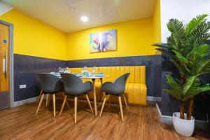 een eetkamer met gele muren en een tafel en stoelen bij A103 Cosy City Loft in Coventry